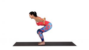 Squat with a rear shoulder exercise using dumbbells and a pilates ball between your knees