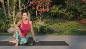 Master Personal Trainer Elaine Reynolds sitting on yoga mat with a roller